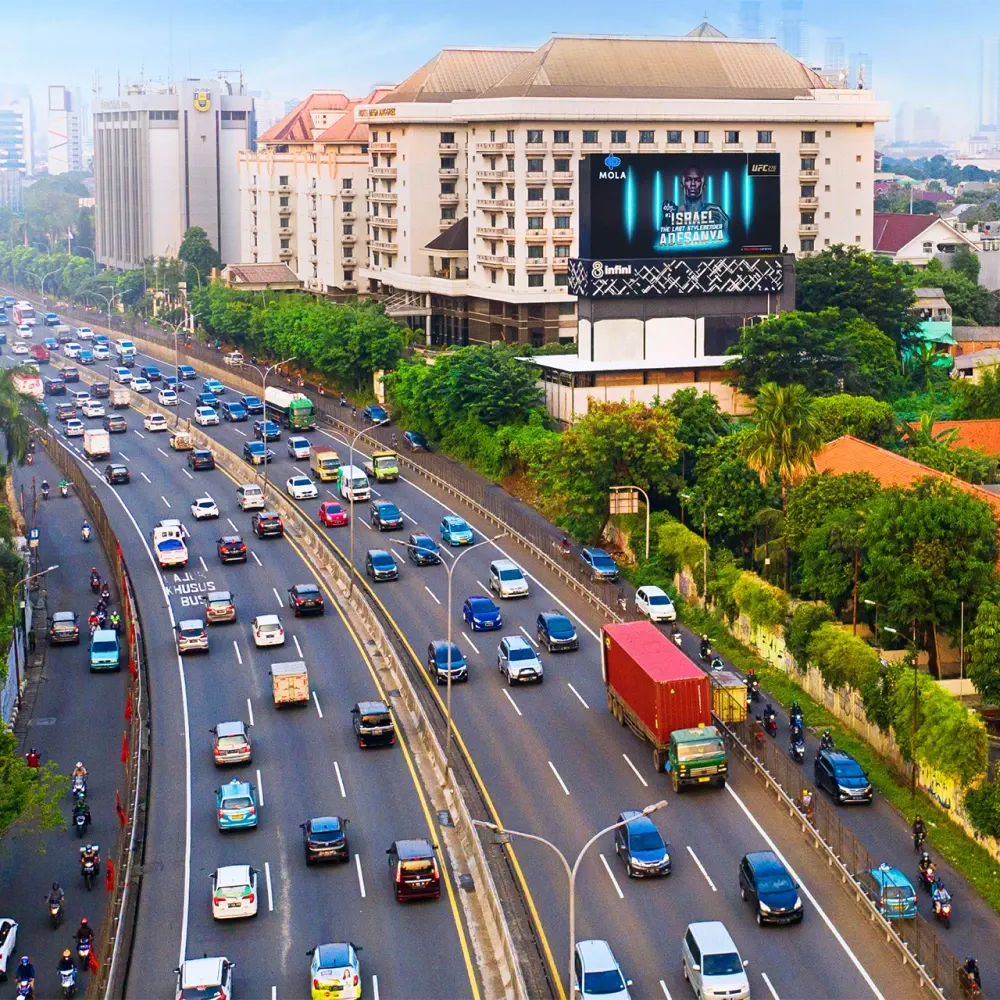 LED Mega Anggrek B showing Mola TV artwork, seen from above with dense traffic on the toll road below
