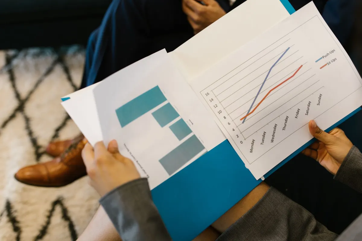 Hands holding report pages with bar and line charts during a meeting