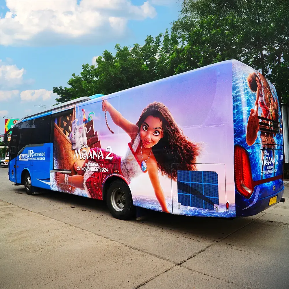 Commuter bus fully wrapped with Disney's Moana 2 campaign on its side and rear, parked on an asphalt road