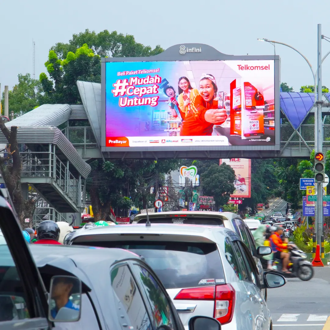 LED videotron 8infini di jembatan penyeberangan Warung Jambu Bogor di bawah langit mendung, dikelilingi pepohonan