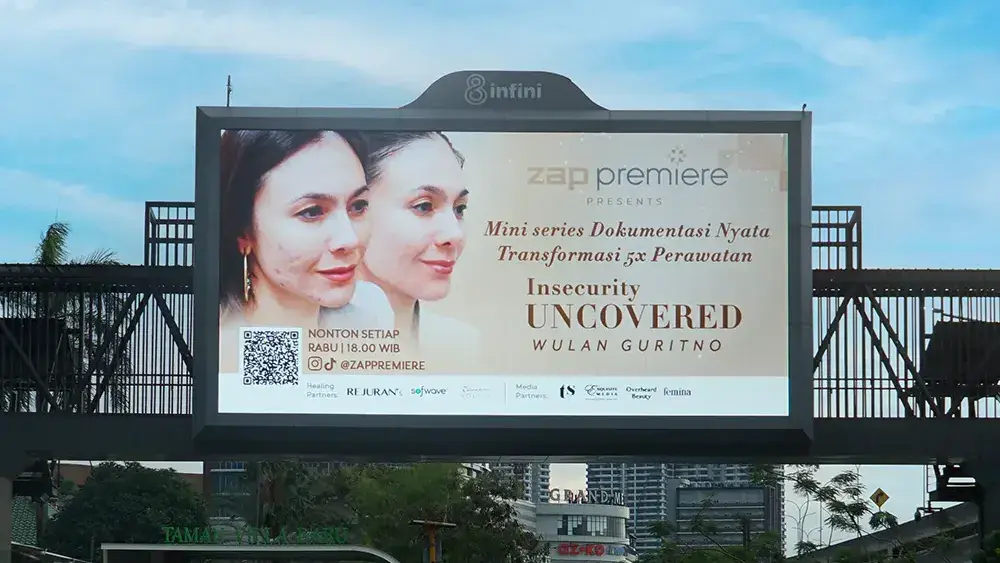 LED videotron on the Metropolitan Mall pedestrian bridge in Bekasi showing a ZAP ad above a rain-wet road with cars and motorbikes below