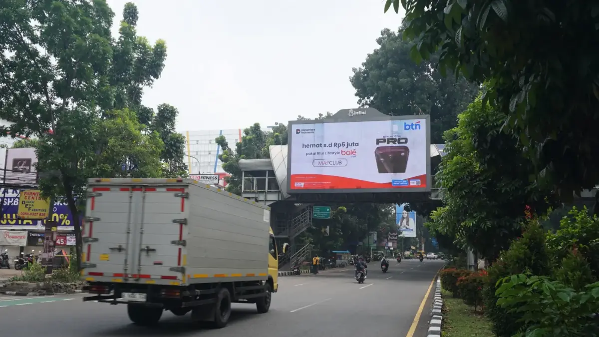 LED videotron 8infini di jembatan penyeberangan kawasan Masjid Raya Bogor, dengan truk dan sepeda motor melintas di jalan berpohon