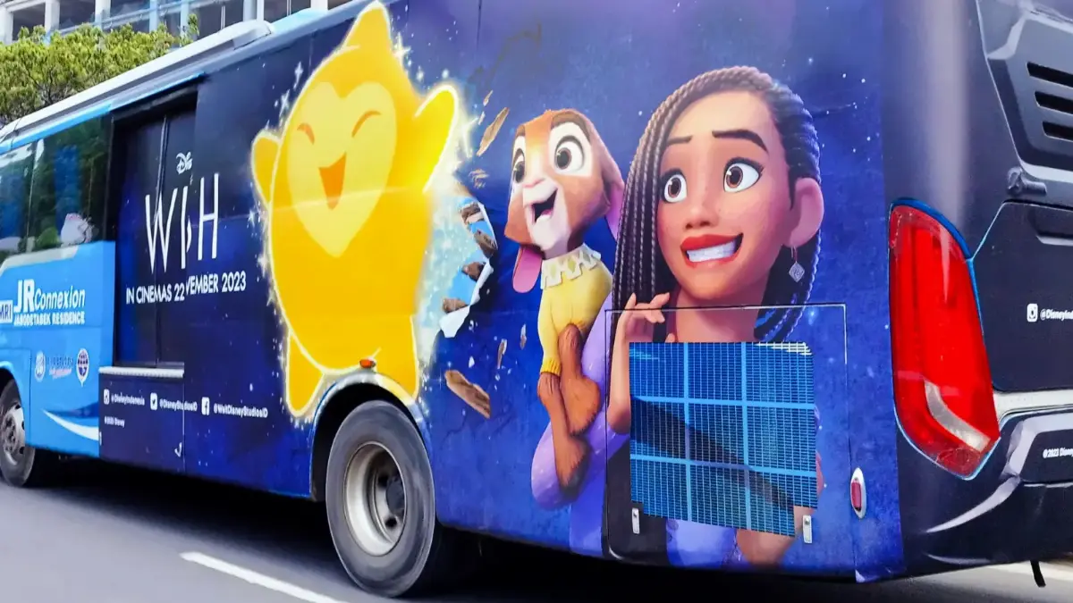 Transjabodetabek bus with a full wrap for Disney's Wish film campaign driving on a Jakarta road