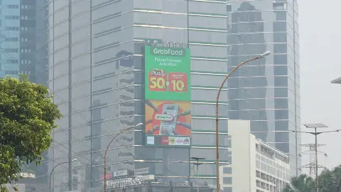 Large portrait LED screen on the facade of a high-rise on Jl. Gatot Subroto, Jakarta, above the Menara Jamsostek sign
