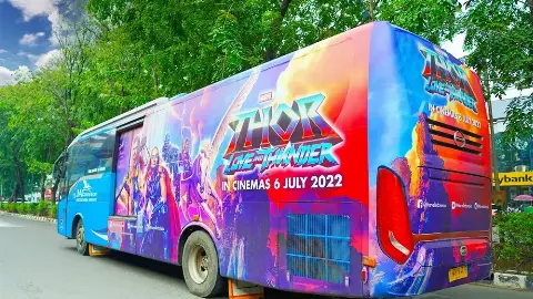 Transjabodetabek bus wrapped in Disney's Thor campaign driving on a Jakarta road