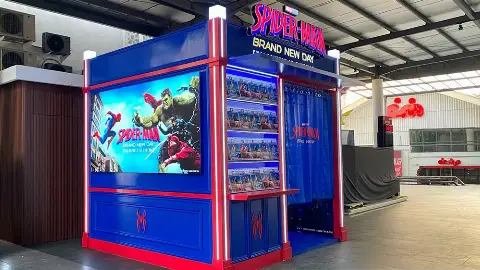 Spider-Man themed booth for Sony Pictures Indonesia with a poster screen, display shelves and a blue-curtained photo booth in a covered open-air area