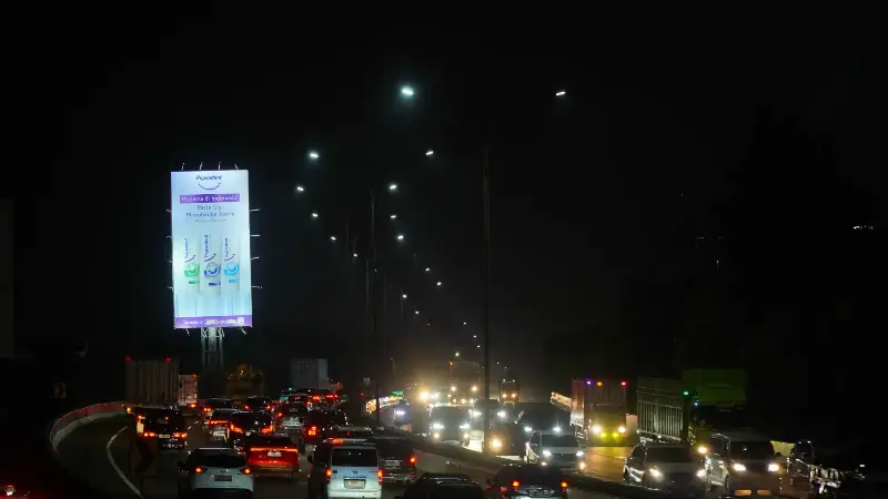 Illuminated Lebak Bulus billboard at night above heavy traffic on Jl. RA Kartini, South Jakarta